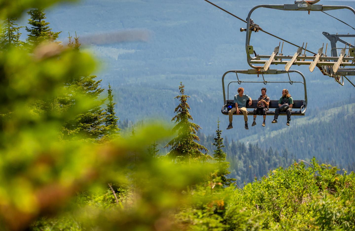 Three people sitting on a chairlift in summer