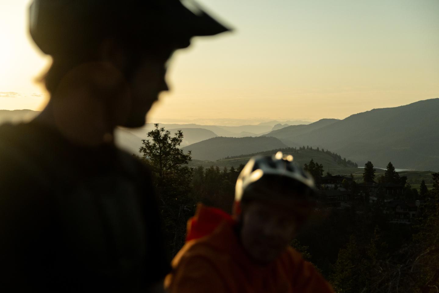 Two bikers out of focus with mountains in the background