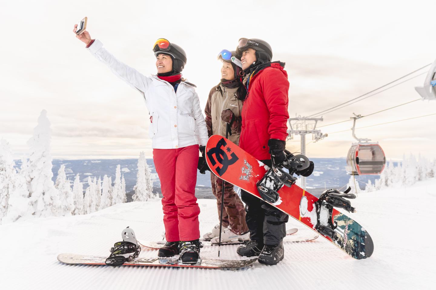 Three people taking a selfie while snowboarding