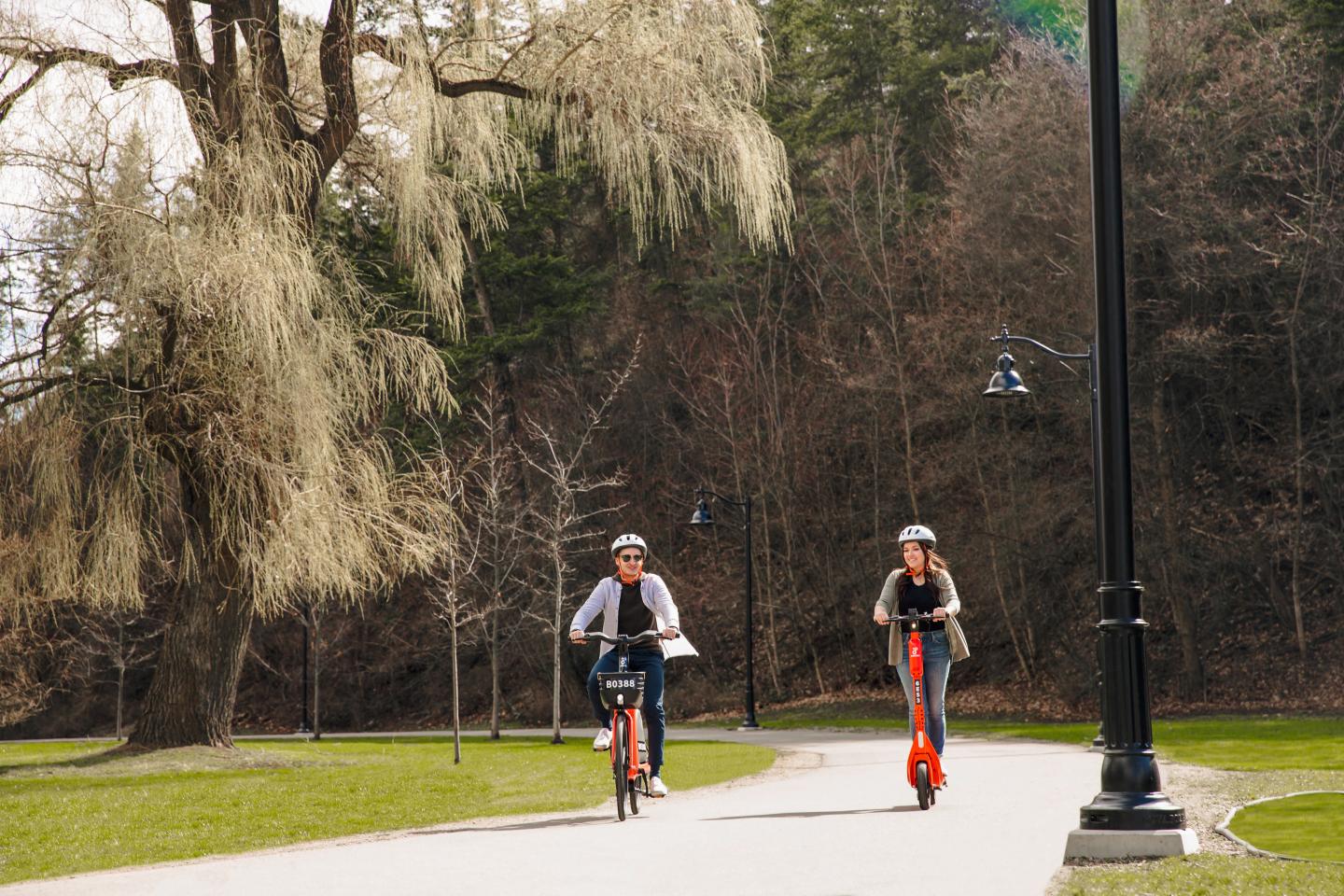 Two people on a bike and a scooter