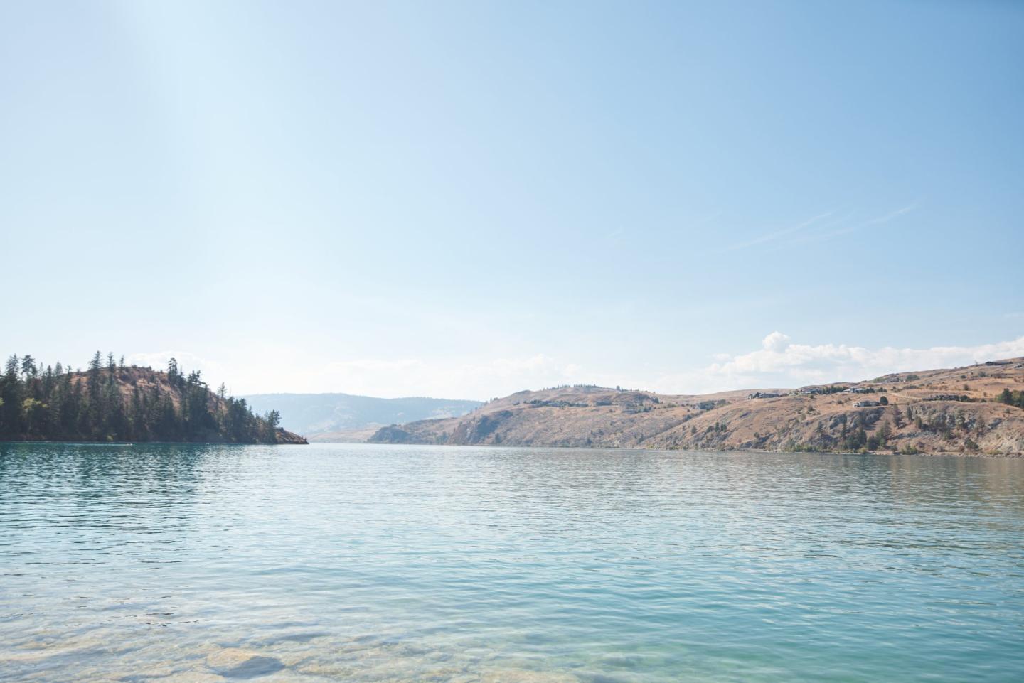 calm teal coloured lake in the mountains with clear blue skies
