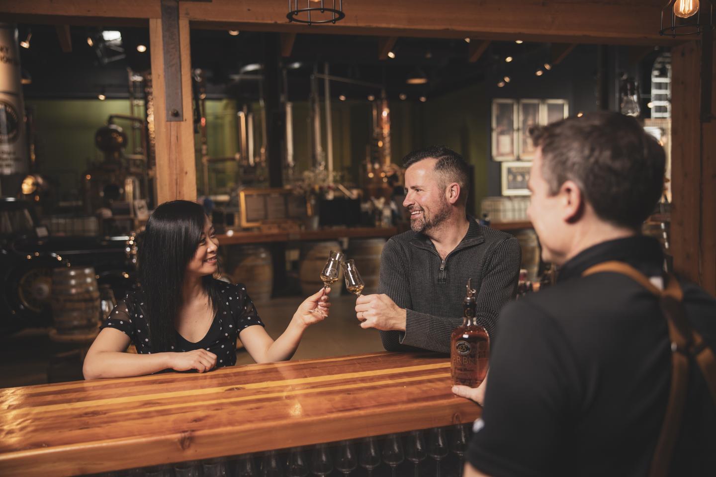 two people clinking glasses inside distillery