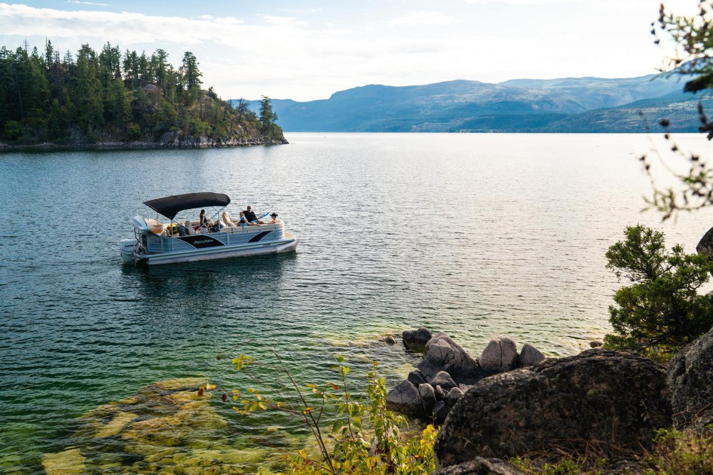 pontoon boat driving across mountain lake