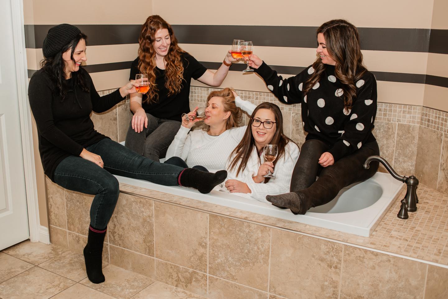 women laughing in bathtub with wine