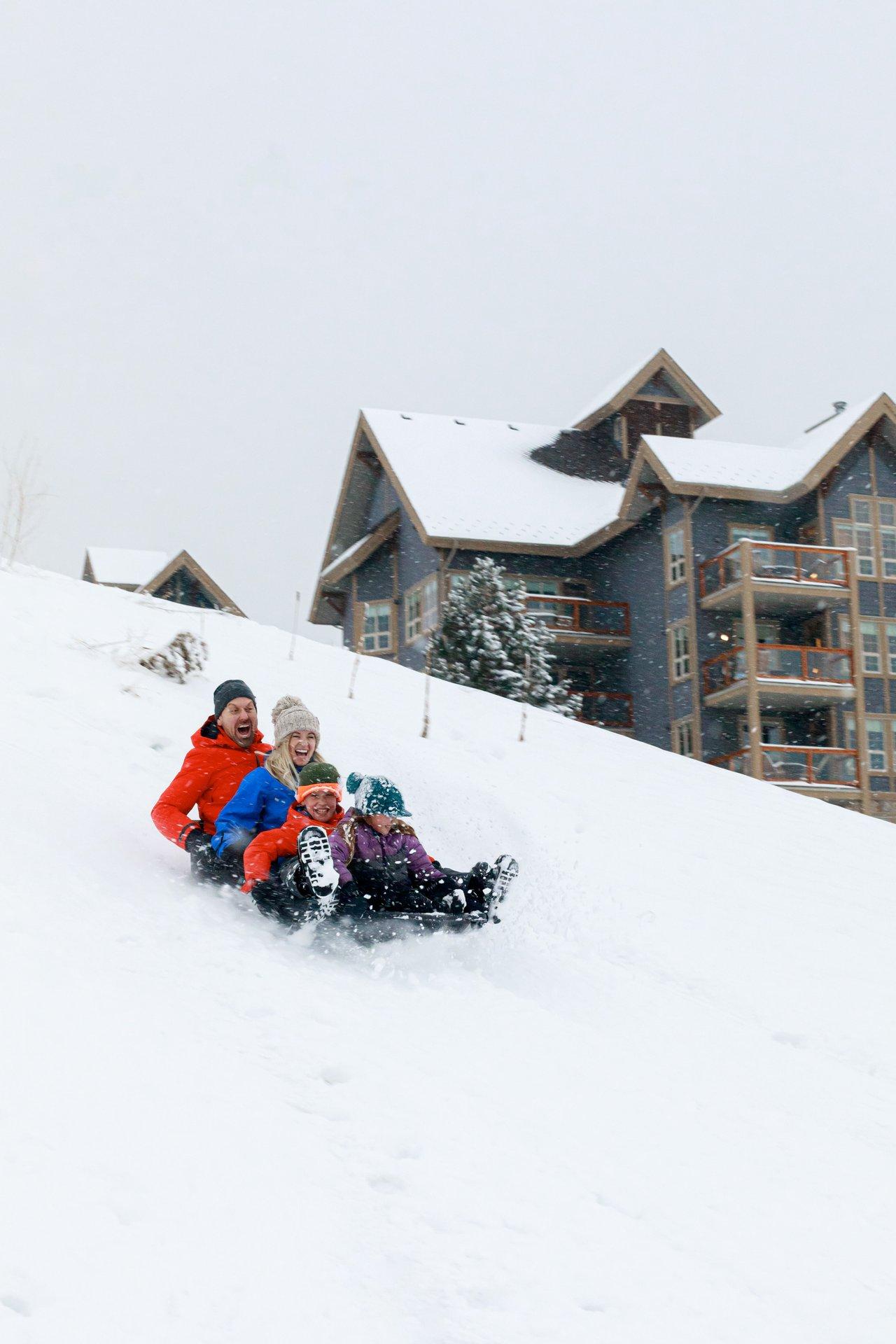 family tobogganing in snow