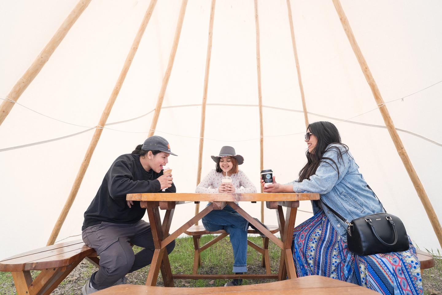 people sitting inside teepee at table