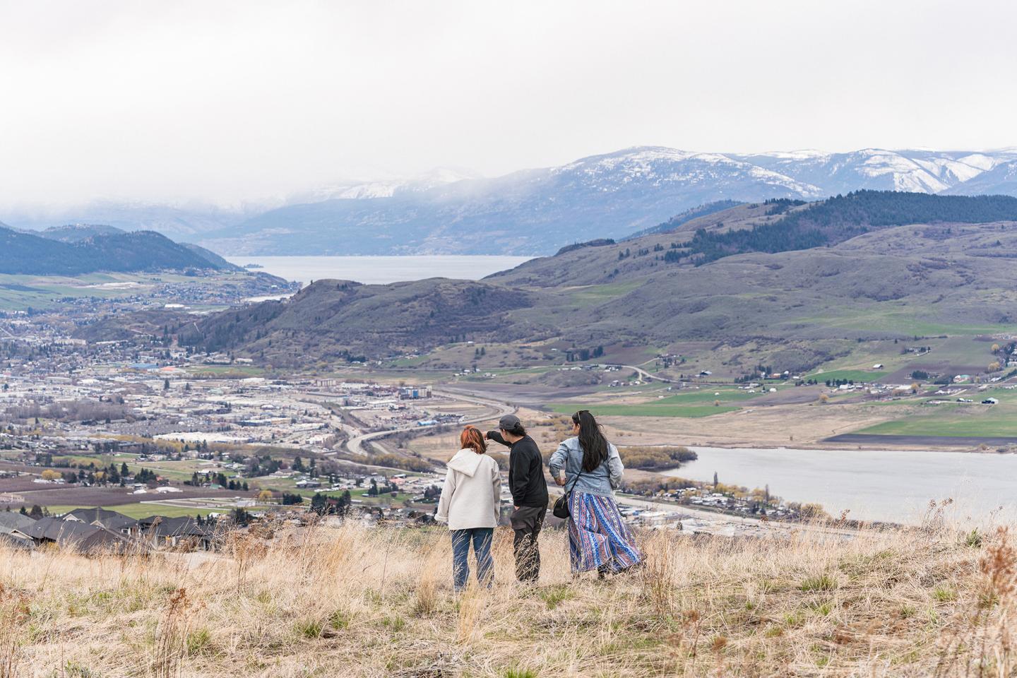 people standing on hillside overlooking valley