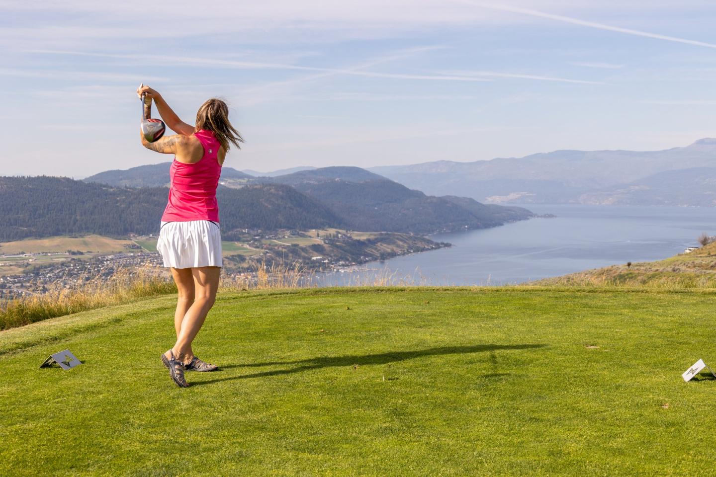 woman golfing with view of Okanagan Lake in background