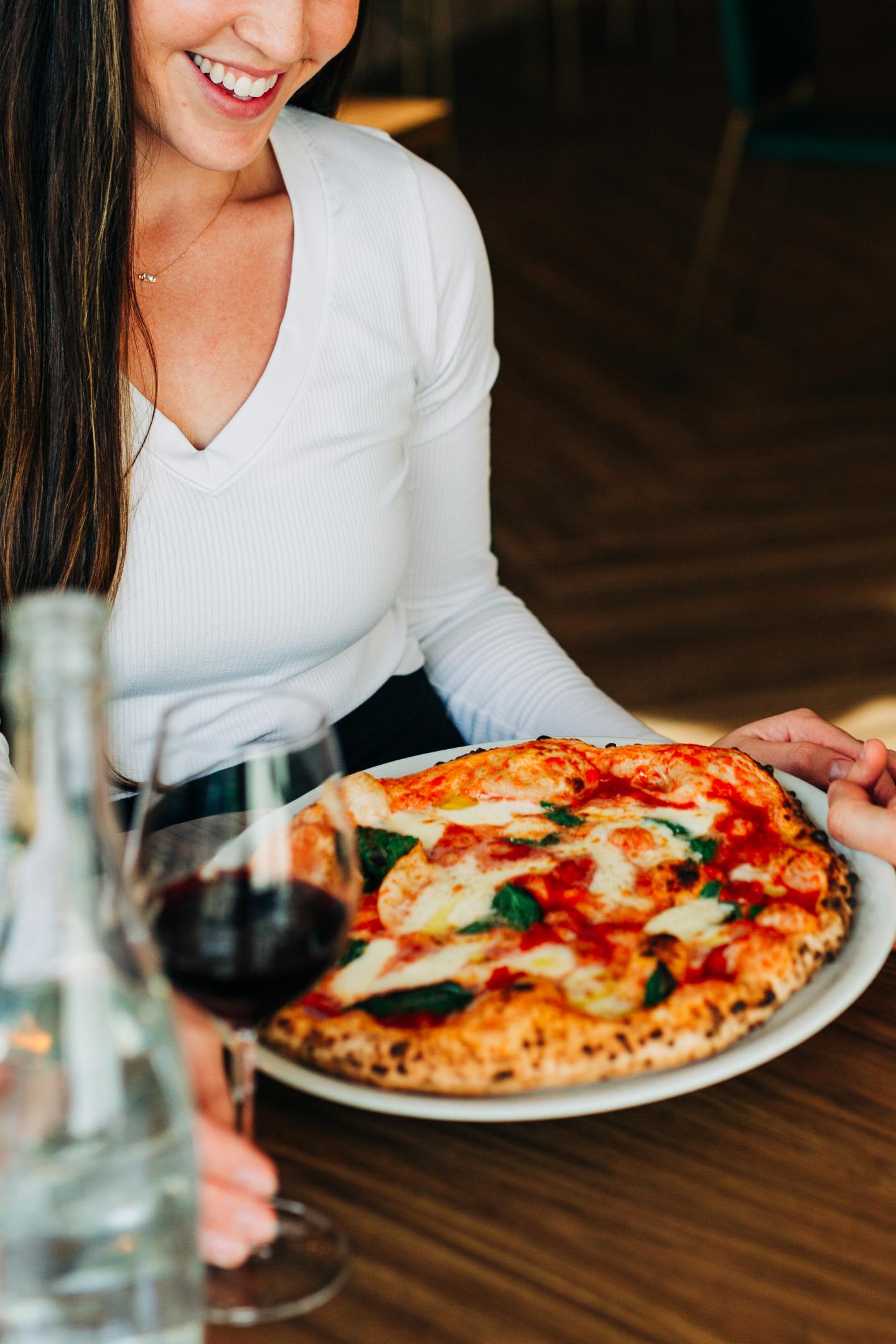 Woman sitting down with pizz and a glass of wine