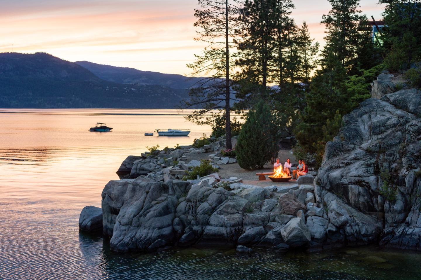 sunset over Okanagan Lake with group having a bonfire on the shore