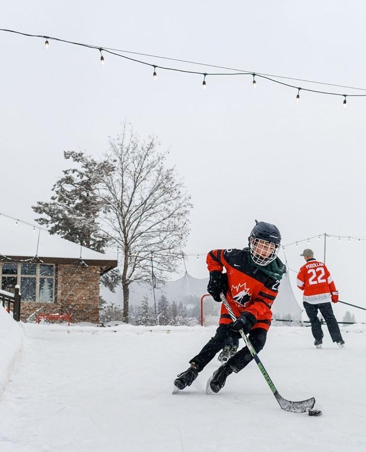 Child skating on rink with hockey stick and puck