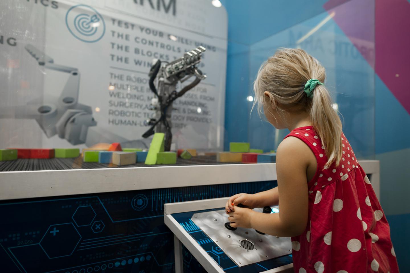 girl playing with robotic arm at science centre