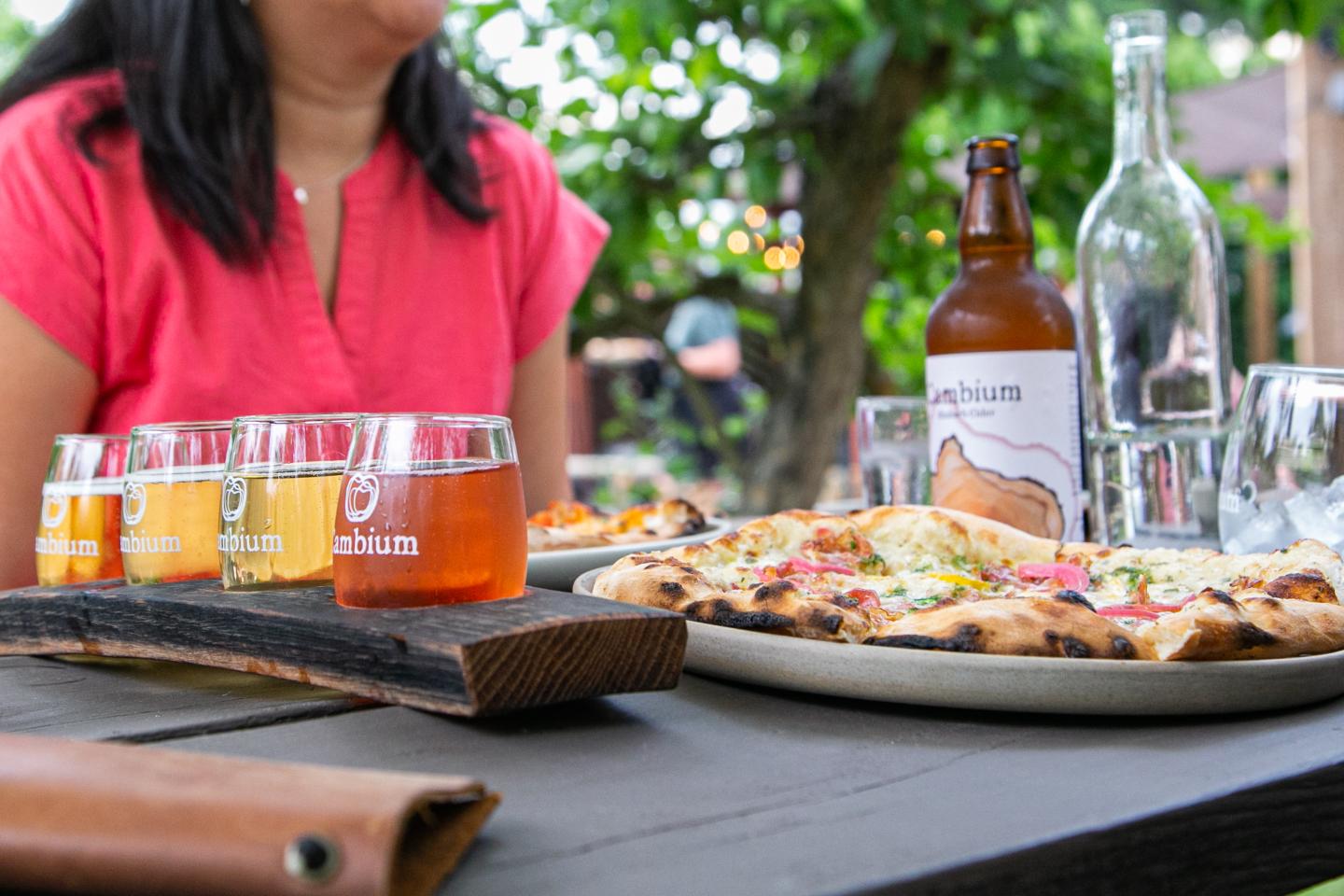 table with pizza and flight of cider