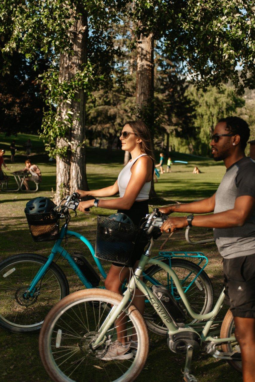 two people walking bikes through Polson Park