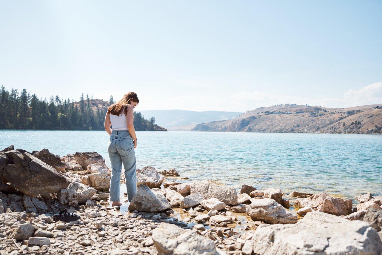 Woman standing barefoot on the shore of Juniper Bay beach in Vernon BC