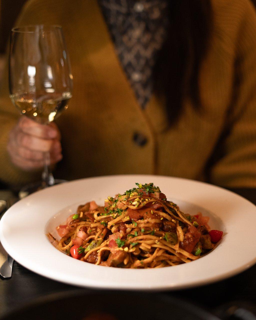 Woman dining at Intermezzo Restaurant with a bowl of pasta and a glass of white wine