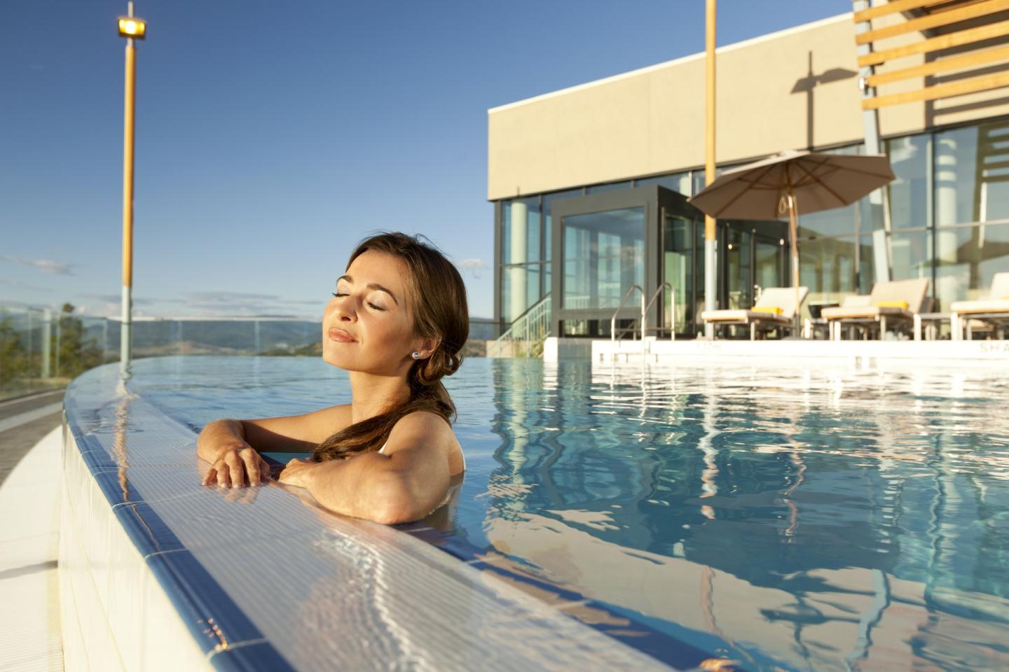 Woman basking in the sunlight in the infinity pool at Sparkling Hill Resort