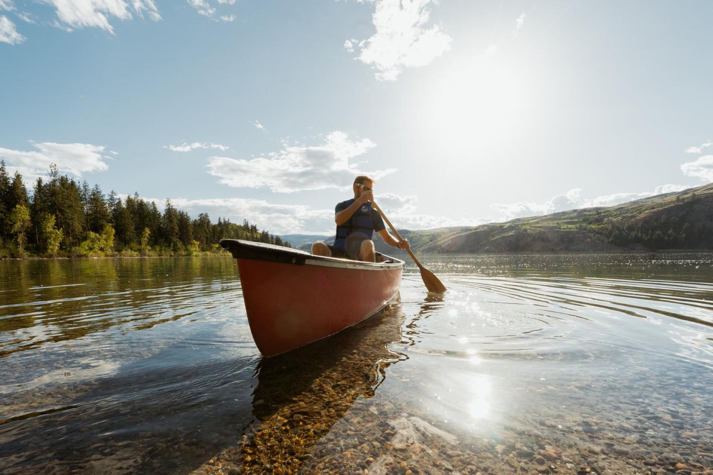 Man on a lake in a red canoe on a sunny day
