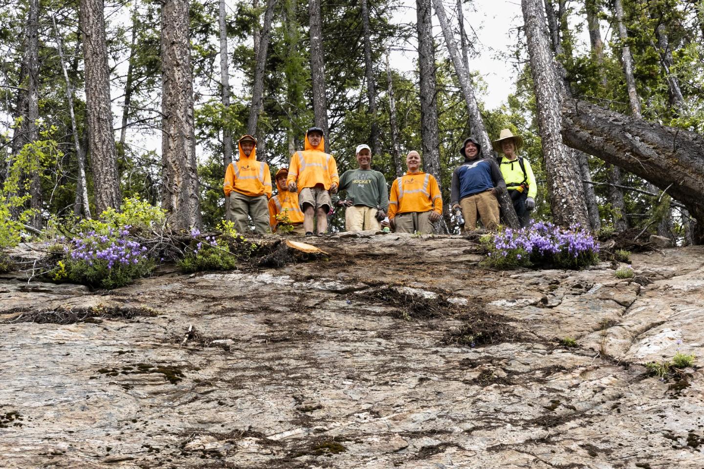 group of trail builders standing at the top of a rock slab