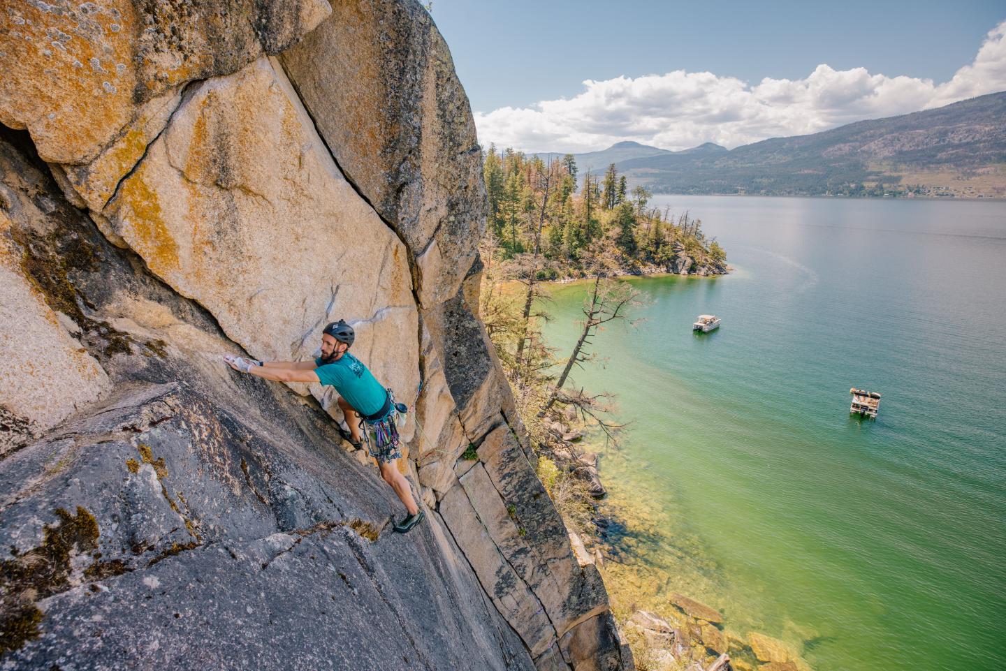 rock climber on wall above pristine lake
