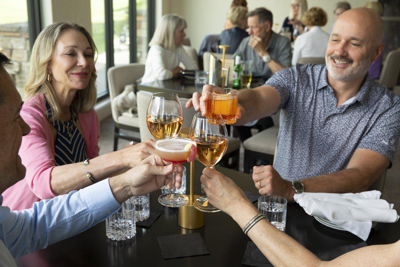 group of 4 adults cheers-ing beverages at a restaurant