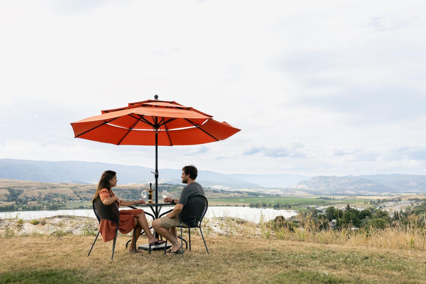 couple sitting at picnic table at winery overlooking lake view