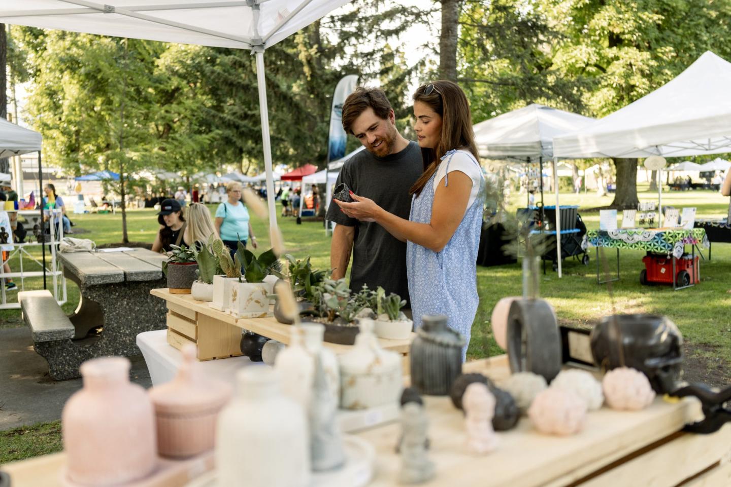 couple looking at items at a booth at an artisan market outdoors