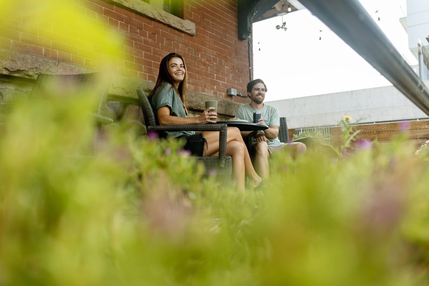 couple sitting at table on patio at coffee shop with flowers in the foreground