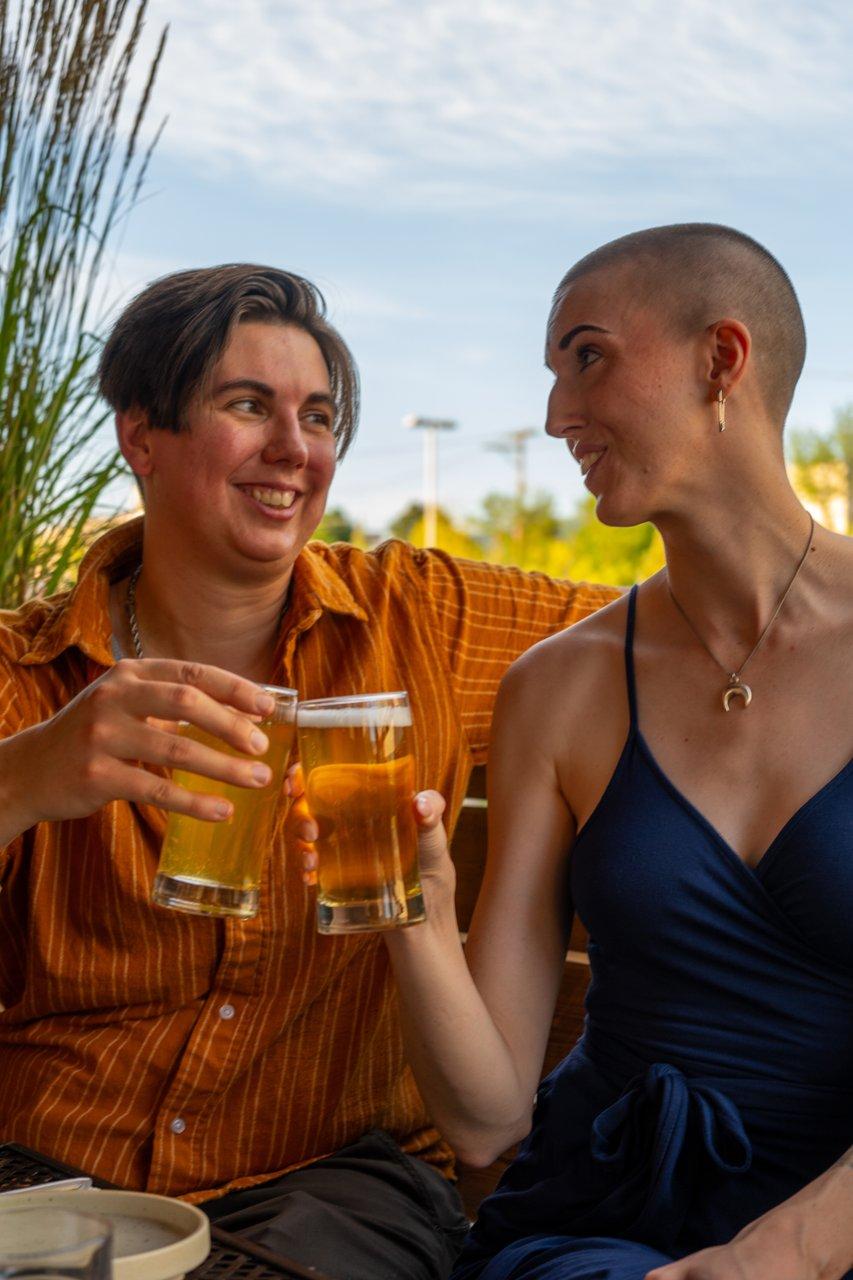 two people holding beers