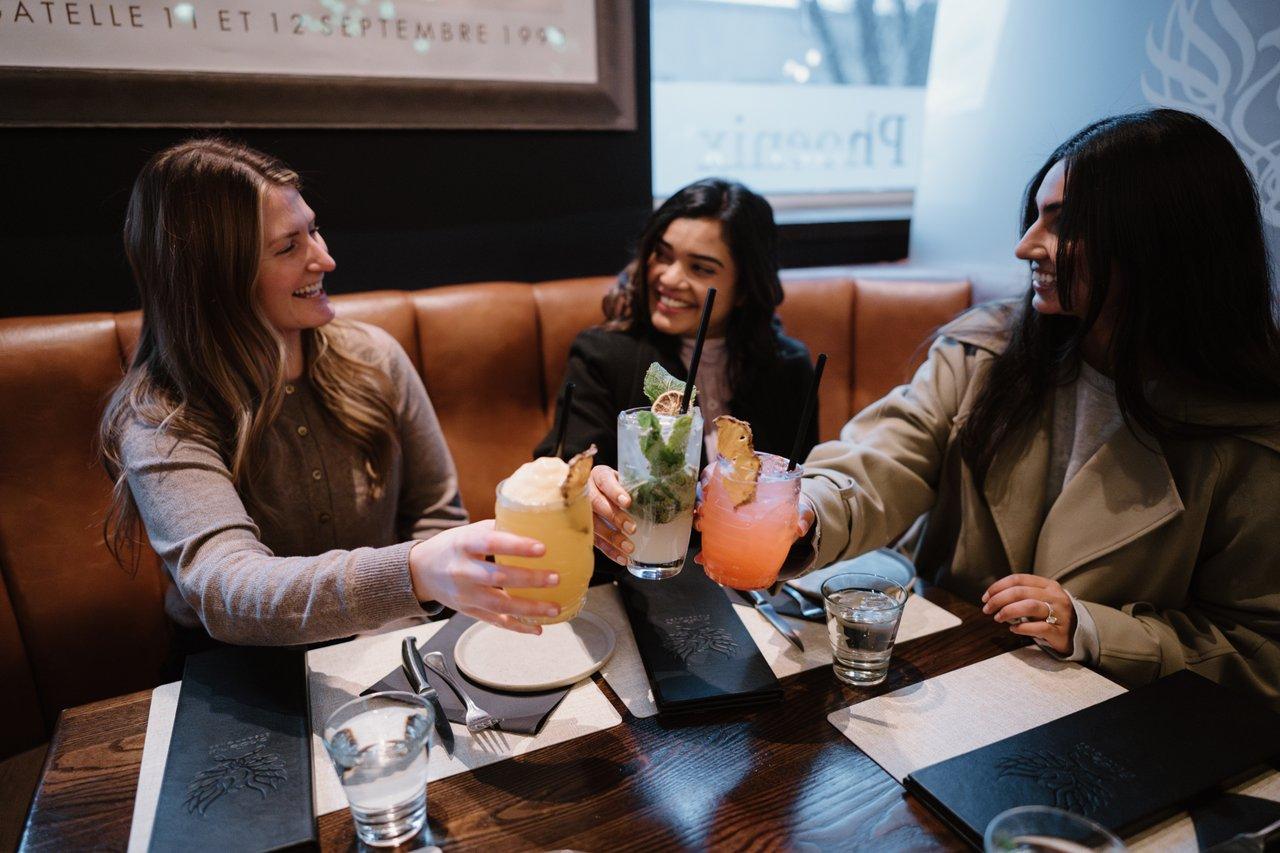 three women cheersing cocktails at a restaurant
