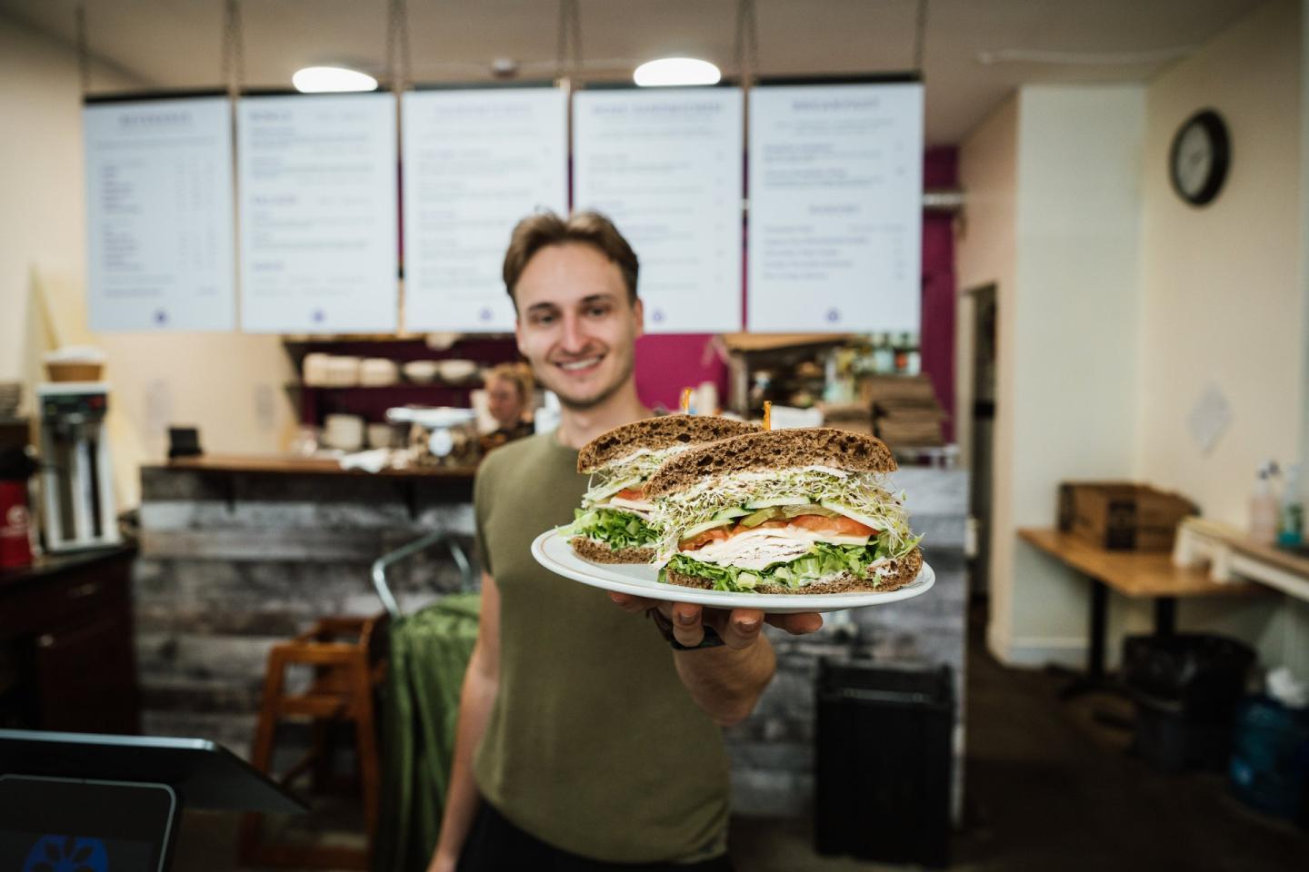 cafe owner with sandwich in hand