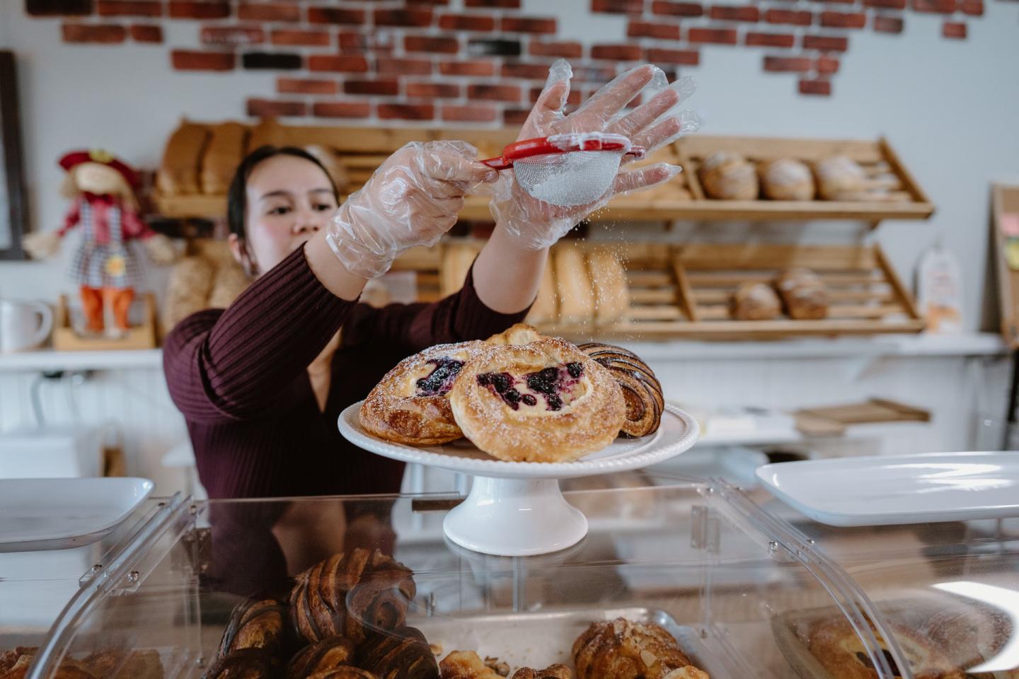 bakery owner sifting powdered sugar on pastries