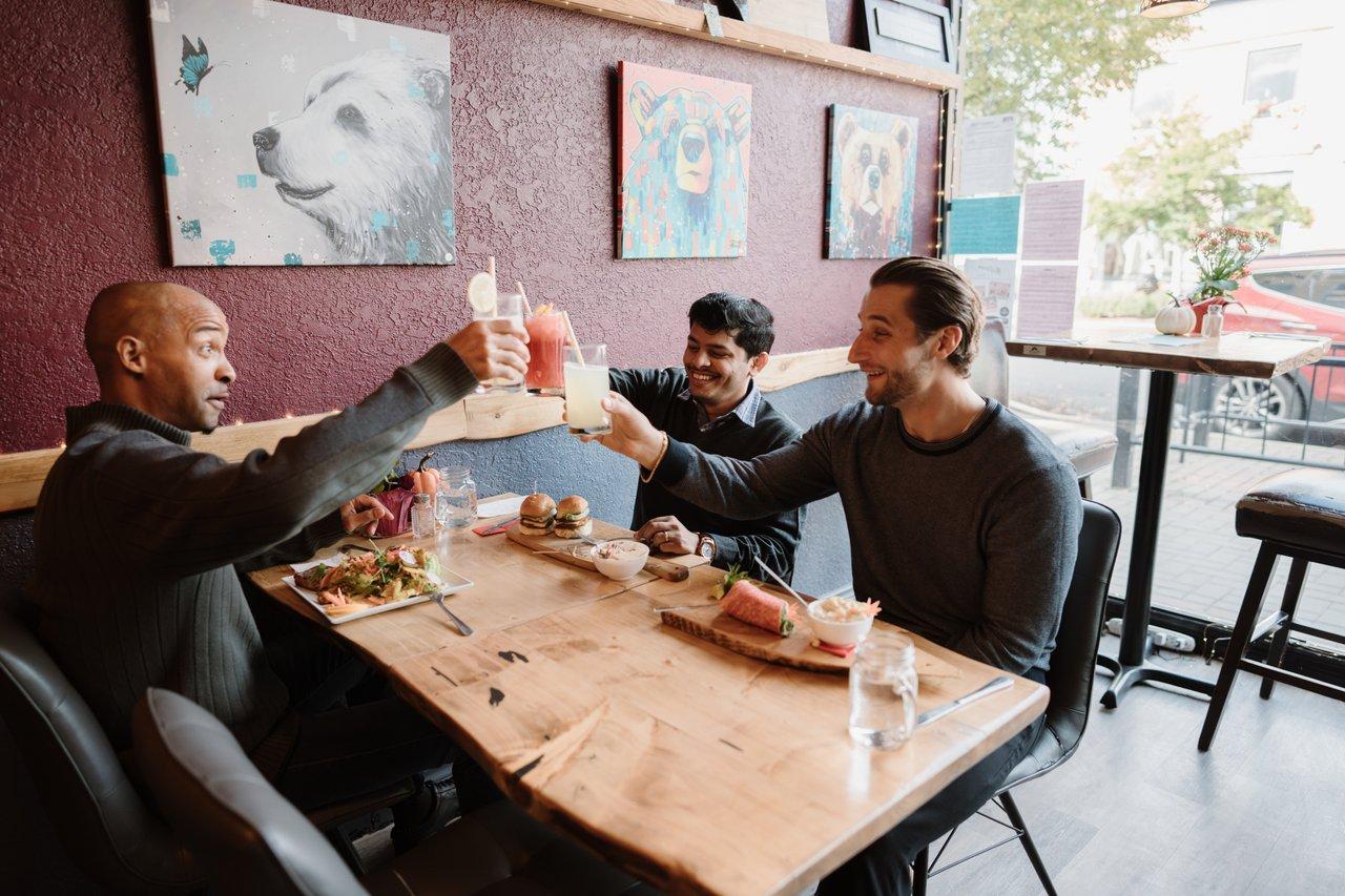 three men eating lunch and cheersing their drinks