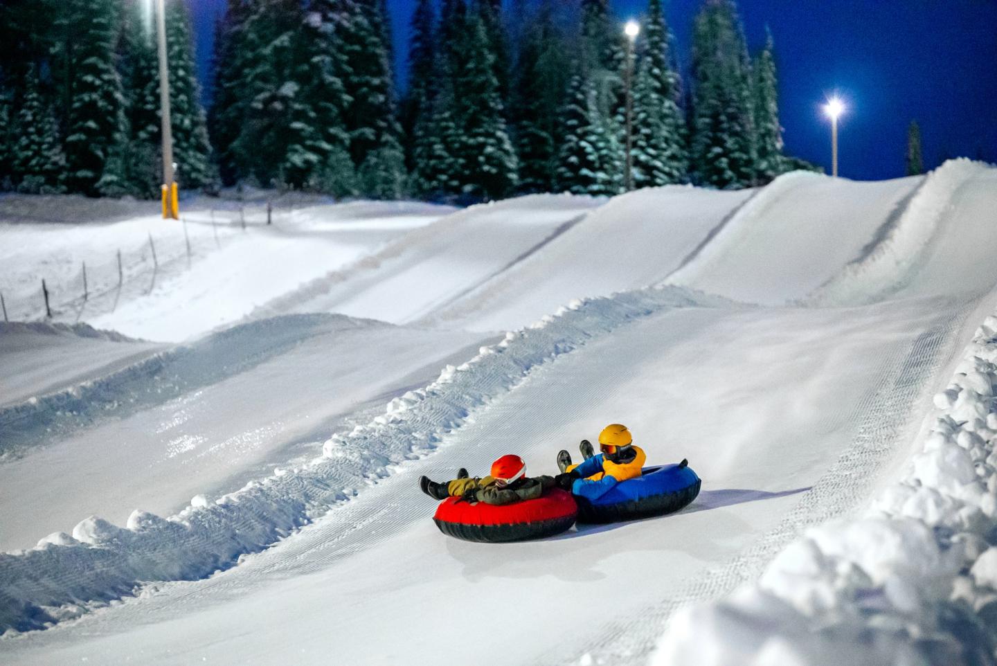 kids riding tubes down snowy hill
