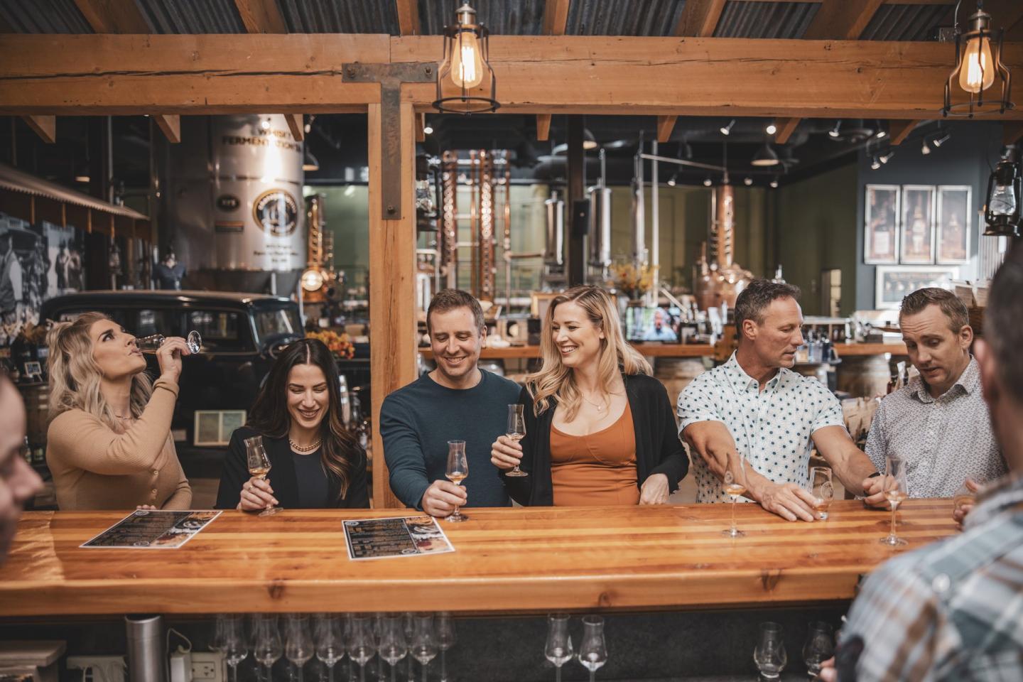 guests of a distillery doing a tasting at a bar