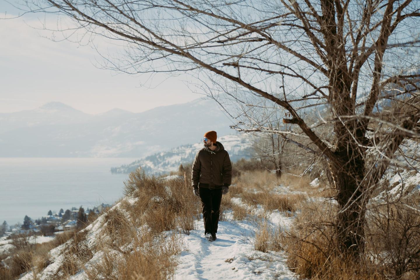 person walking on trail in the snow with lake view in background