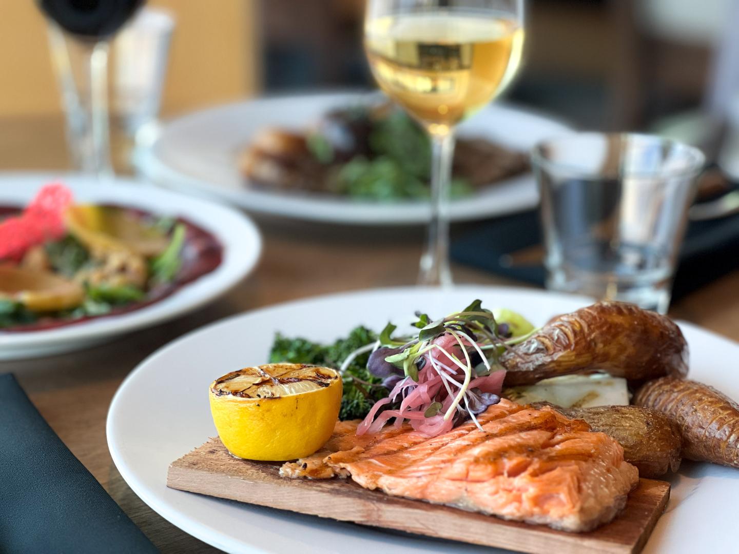 steelhead trout dish a fine dining restaurant with wine glass in background