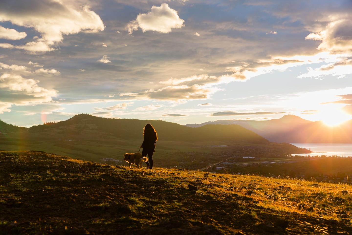 women and dog hiking at sunset