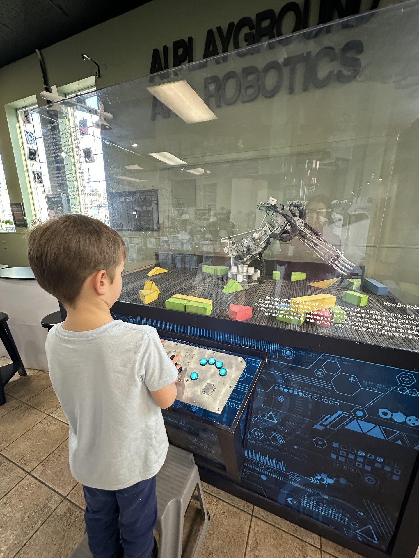 kid playing with robotic arm at science centre