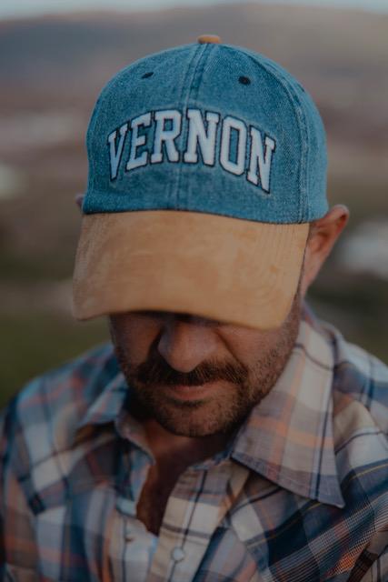 close up of person wearing hat that says 'Vernon' on it
