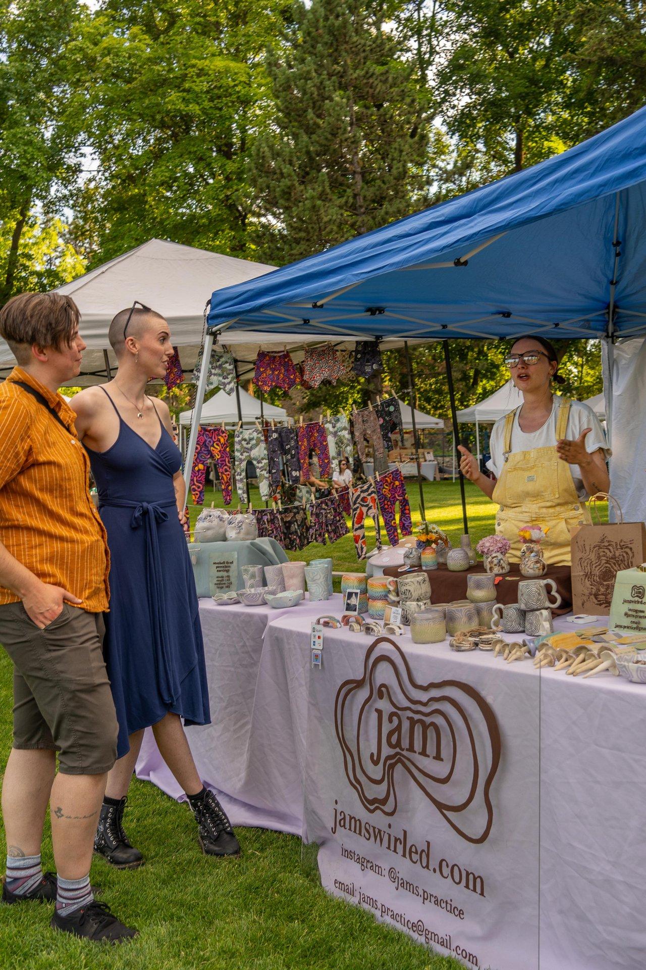 couple browses market stand with person selling giftware