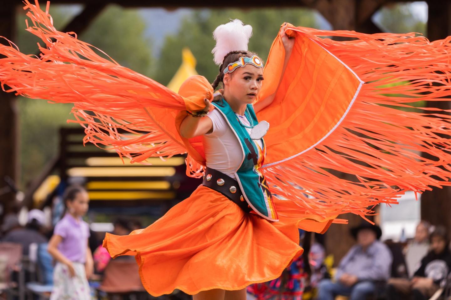 person dancing at a powwow in an orange dress