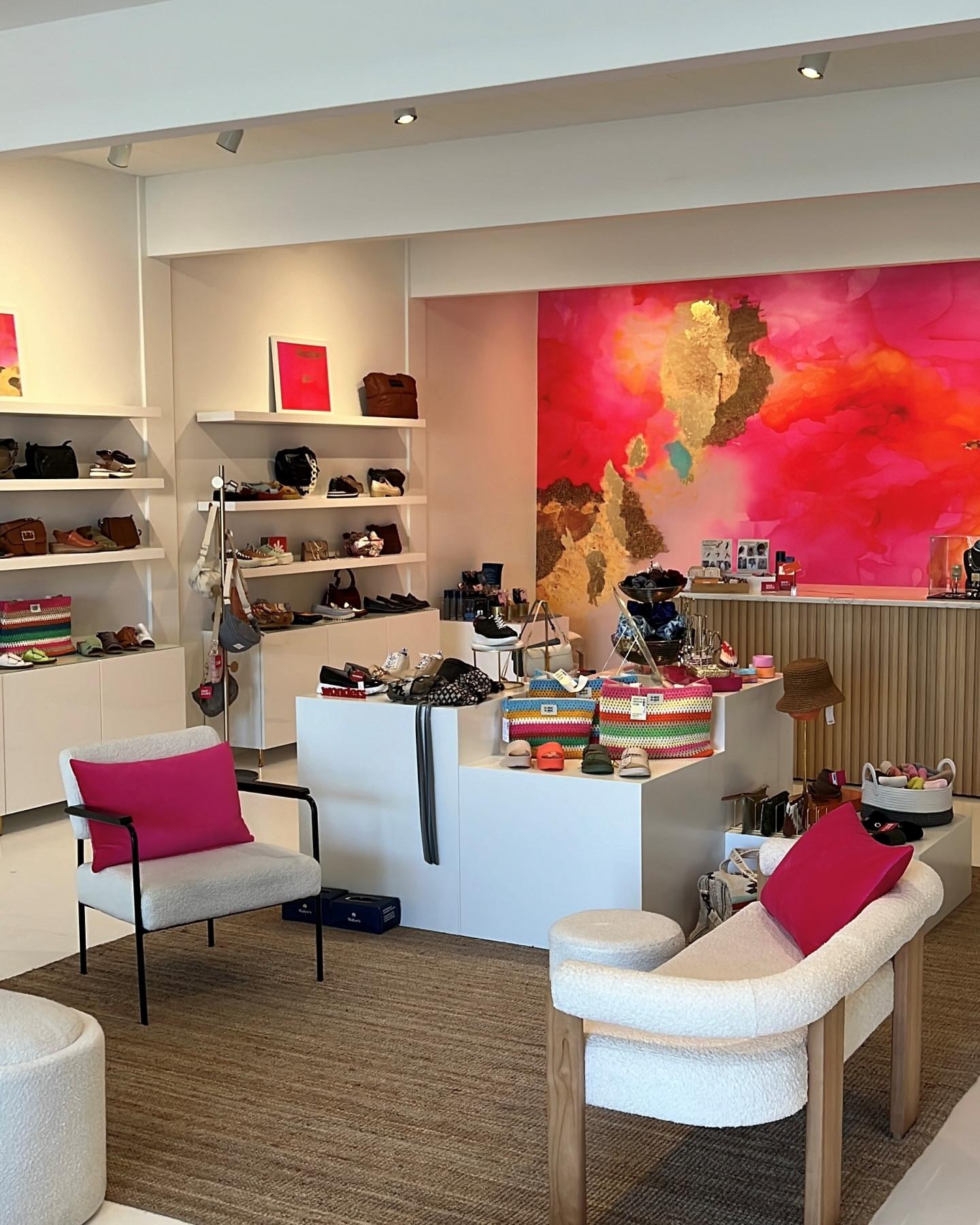 Store interior with bright artwork, white shelves, and cushioned seating.