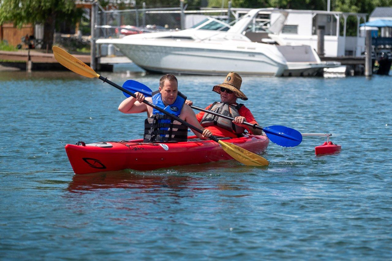 Two people kayaking in a red kayak on a sunny day, blue paddles in motion.