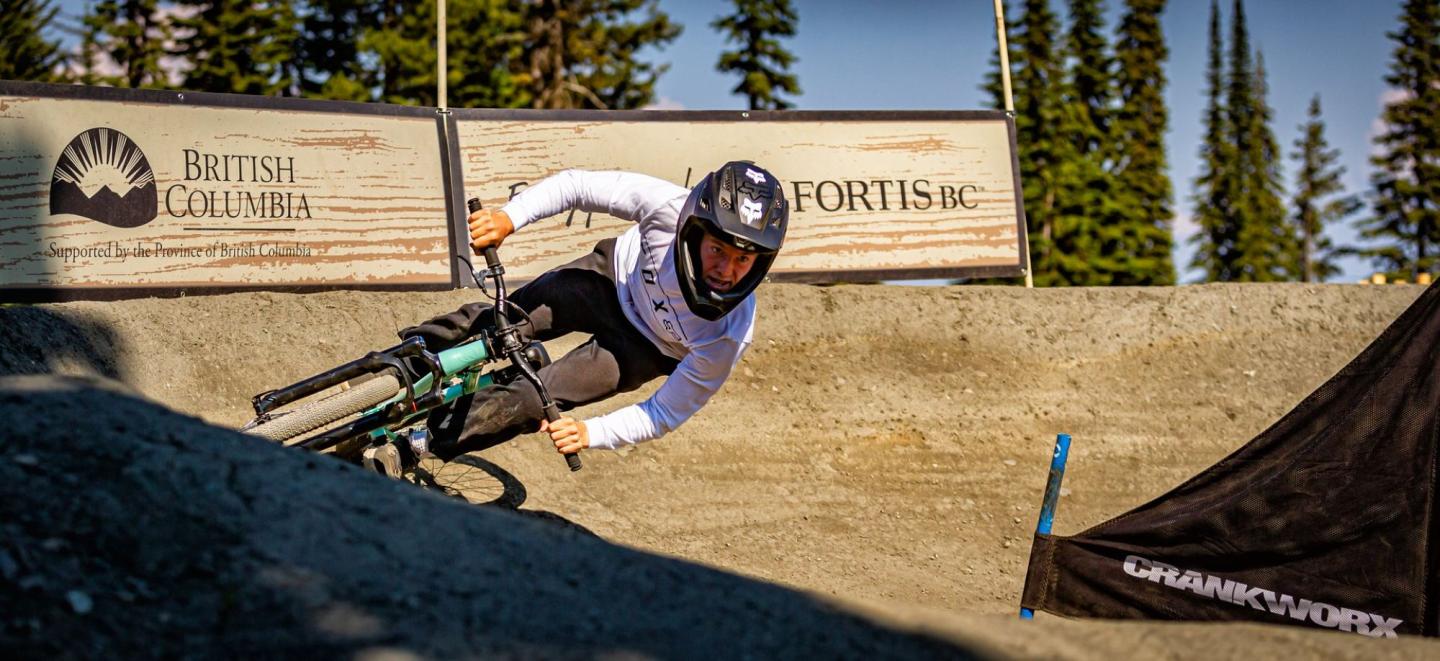 Cyclist in motion on dirt track in a forested setting.