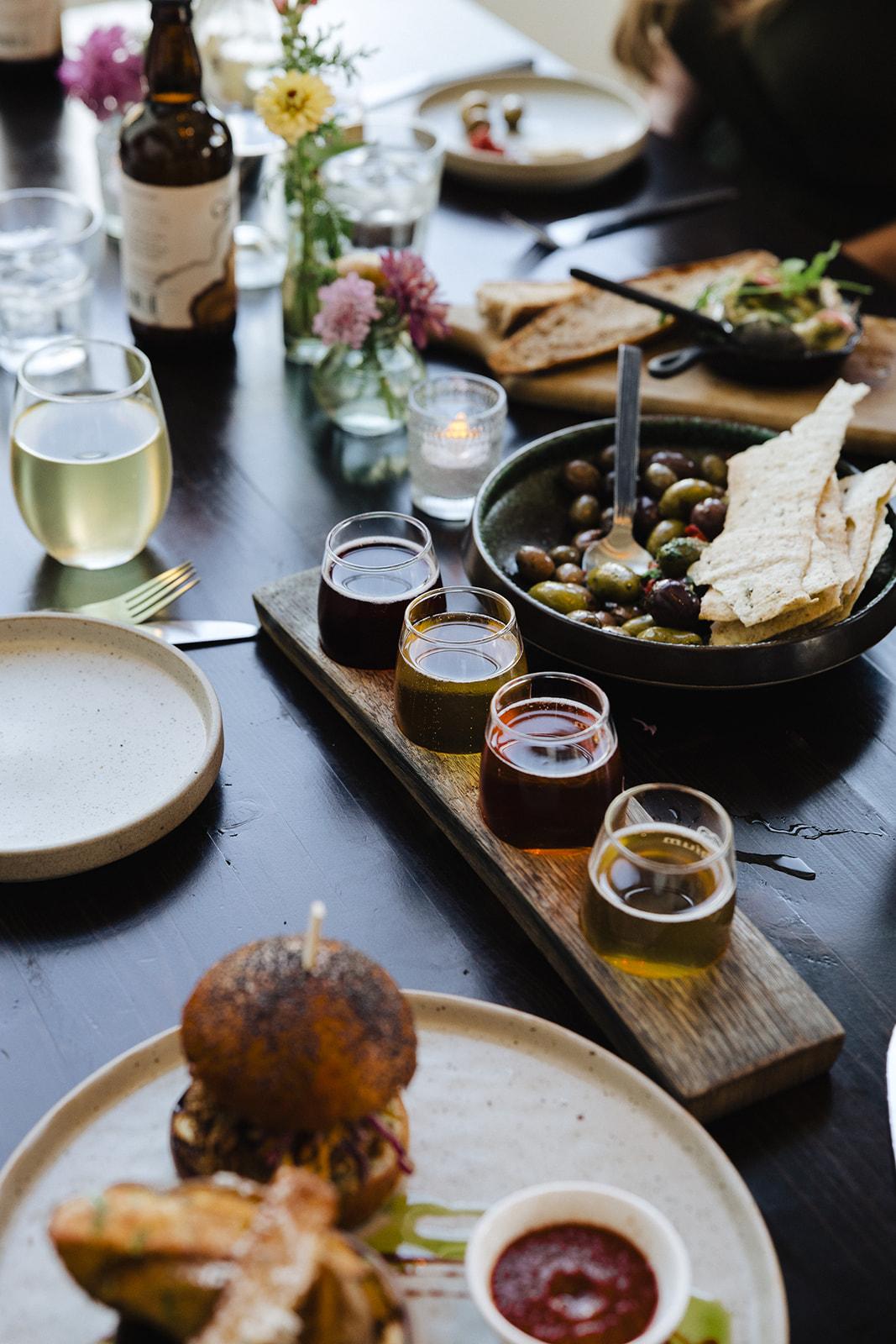 Dining table with appetizers, drinks, and flowers.