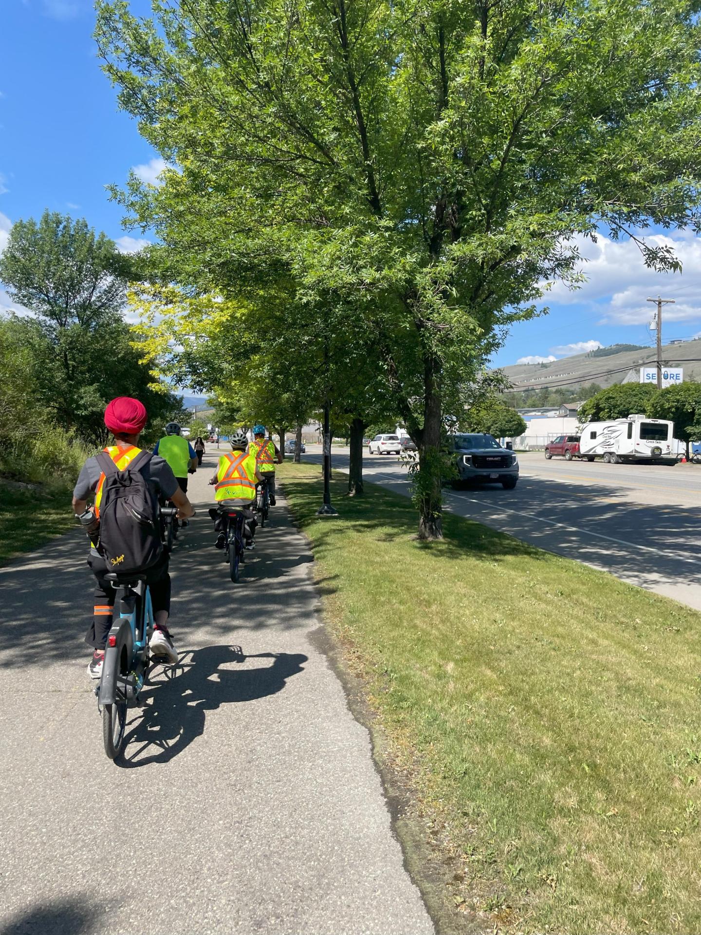 youth climate corp students riding ebikes down sidewalk with trees