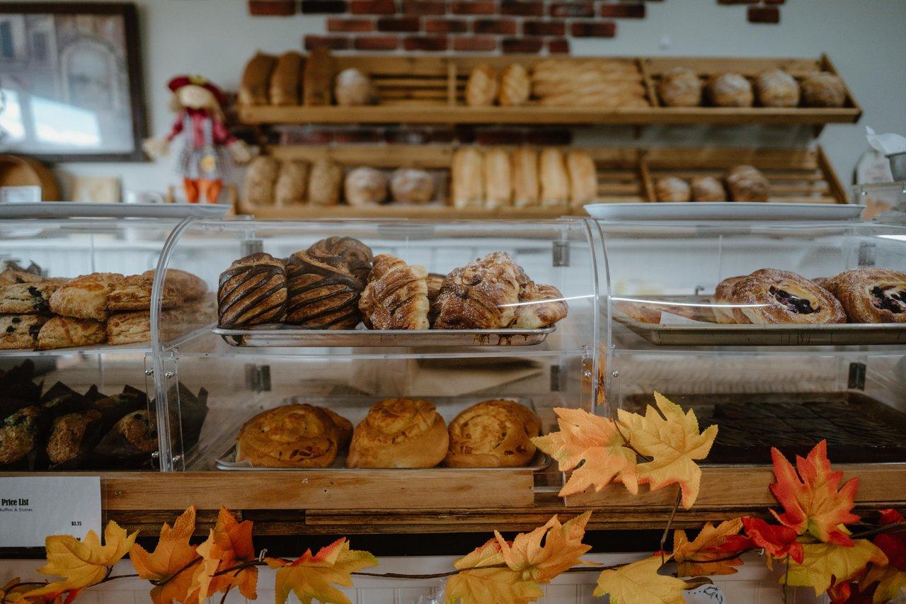 Bakery display with assorted breads and pastries, decorated with autumn leaves.