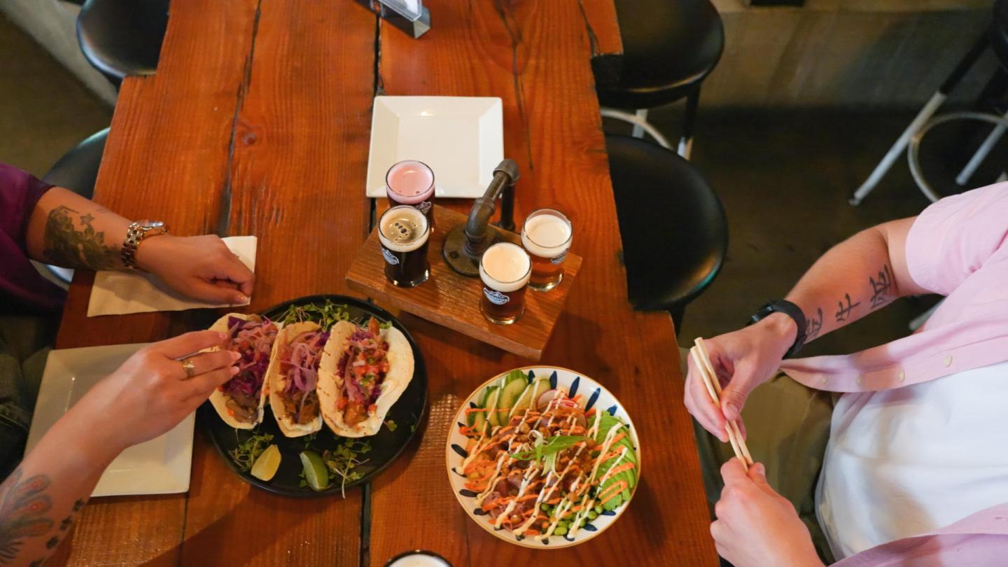 Two people at a table with tacos and beverages.