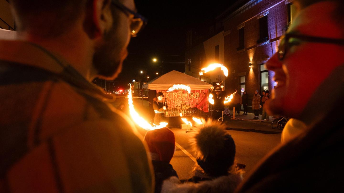 Fire performers entertain a street crowd at night.